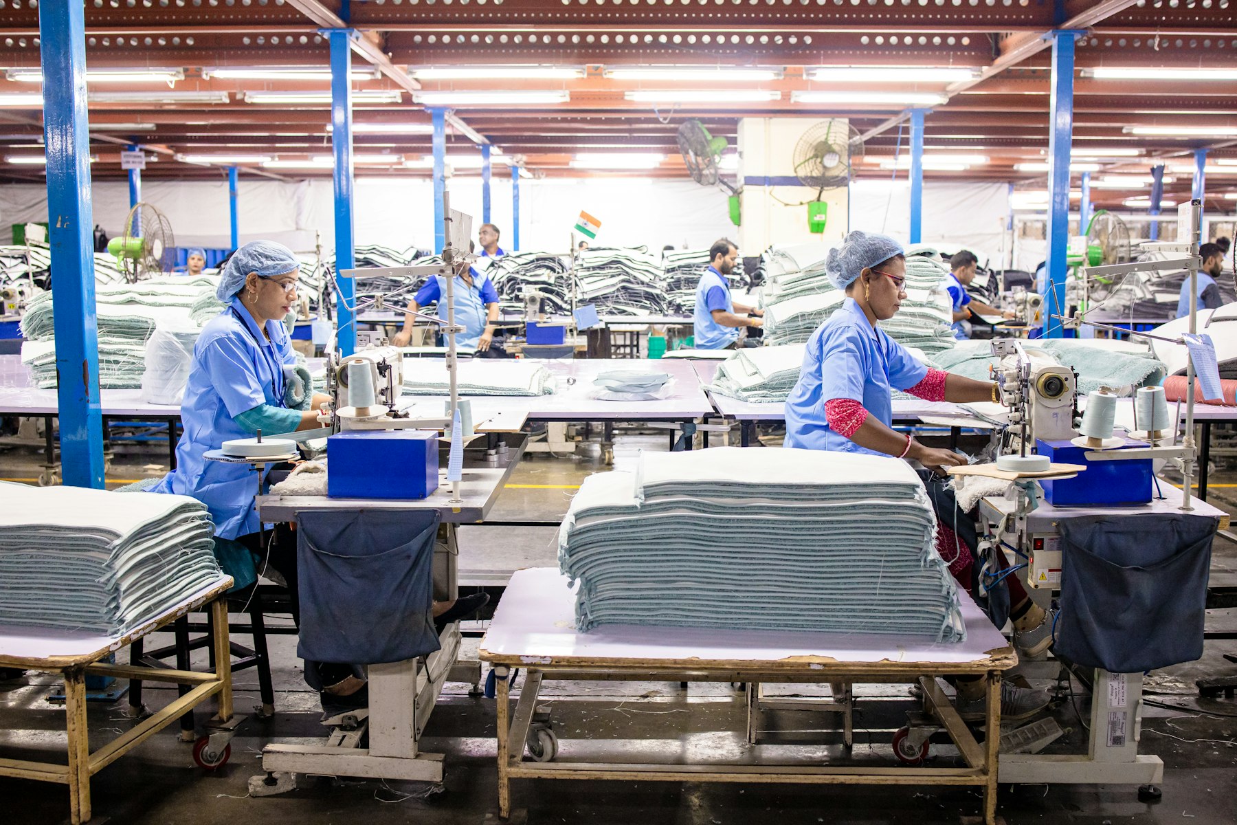 Workers and machinery processing white textiles in a large industrial facility
